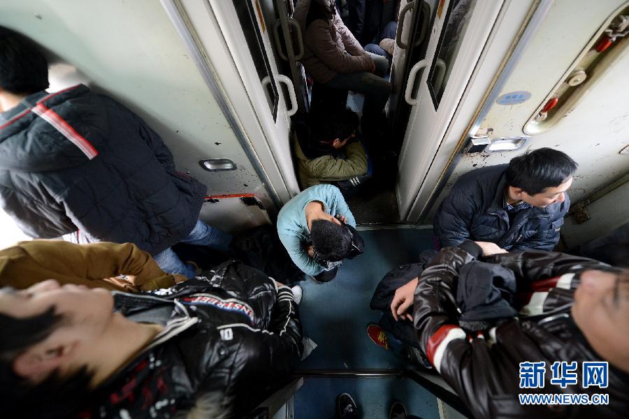 A man without seat crouches in the narrow corridor of a training traveling toward Qingdao, Jan. 19, 2013. (Photo/Xinhua) 