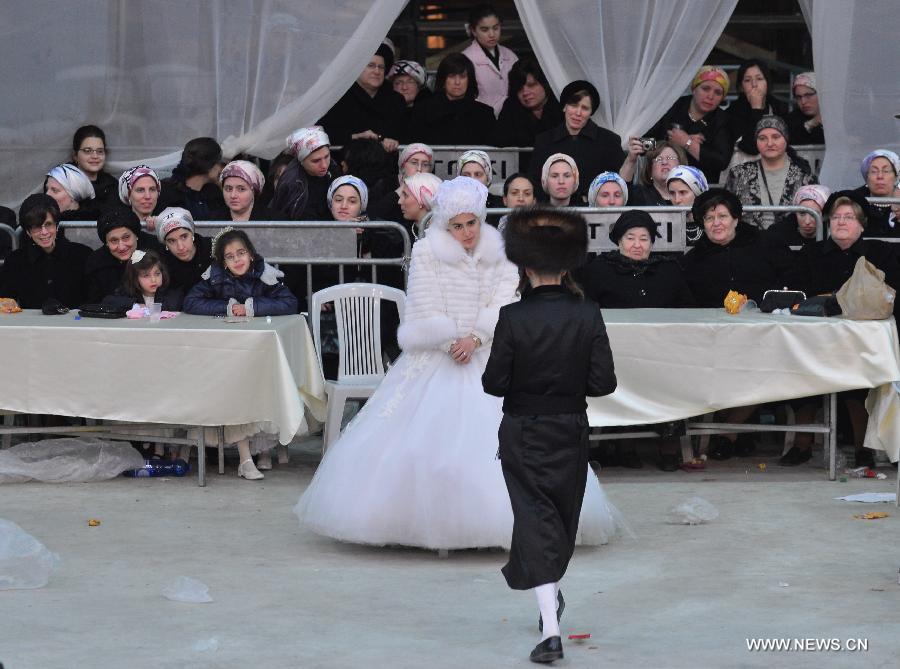 The groom Moshey Chaim walks to invite his bride, the first granddaughter of Grand Rabbi of the Satmar hassidic dynasty Rabbi Zalman Leib Teitelbaum, to dance during their wedding in Israeli town of Beit Shemesh, on Jan. 24, 2013. The wedding was held here from the evening of Jan. 23 to the morning of Jan. 24. Some 5,000 guests attended the traditional Jewish wedding. (Xinhua/Yin Dongxun)