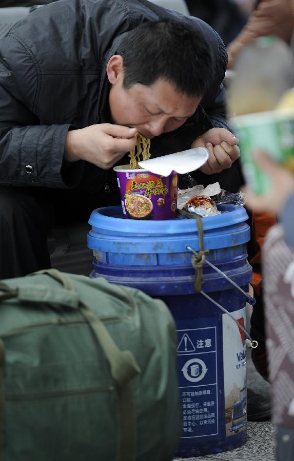 A passenger eats instant noodle while waiting to board a train at the Yinchuan Railway Station in Yinchuan, capital of northwest China's Ningxia Hui Autonomous Region, Jan. 25, 2013. The most important Chinese holiday, the Spring Festival, falls on Feb. 10 and migrants want to get home to see their families. The Ministry of Railways forecast the holiday travel rush, which starts on Jan. 26, will last until March 6. (Xinhua/Wang Peng) 
