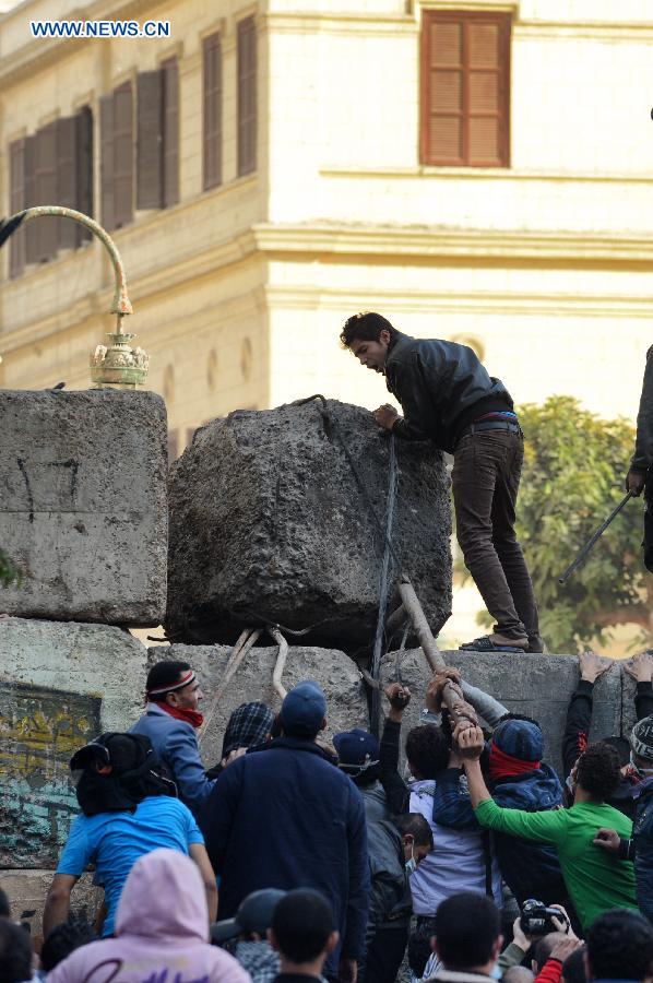 Protesters tear down the cement wall set up by police near Cairo's Tahrir Square on Jan. 25, 2013, during a massive demonstrations held nationwide to mark the second anniversary of the 2011 unrest that toppled former president Hosni Mubarak. (Xinhua/Li Muzi)
