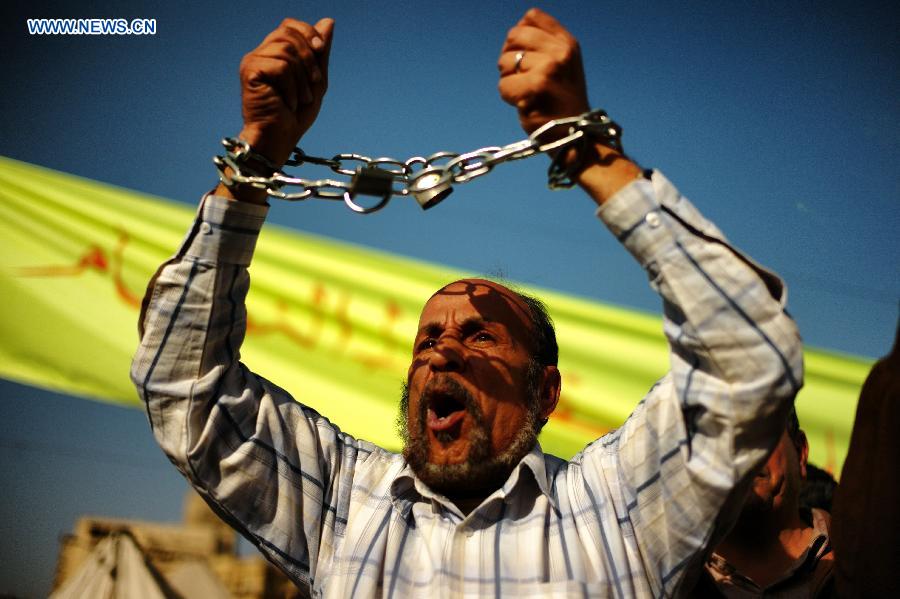 A protester with his hands chained shouts slogans at the Cairo's iconic Tahrir Square on Jan. 25, 2013, during a massive demonstrations held nationwide to mark the second anniversary of the 2011 unrest that toppled former president Hosni Mubarak. (Xinhua/Li Muzi) 