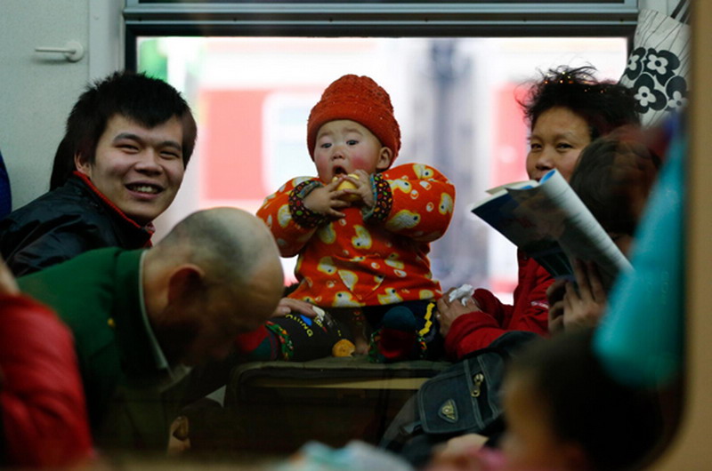 A baby eats an apple on a train at Beijing West Railway Station, Jan 26, 2013.(Photo/Xinhua)