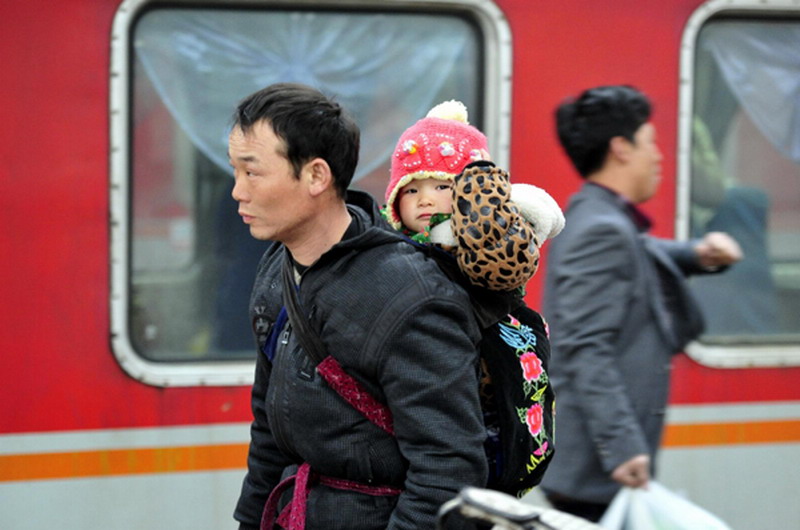 A man and his baby wait to board a train at Jinan Railway Station in Shandong province, Jan 26, 2013. (Photo/Xinhua) 