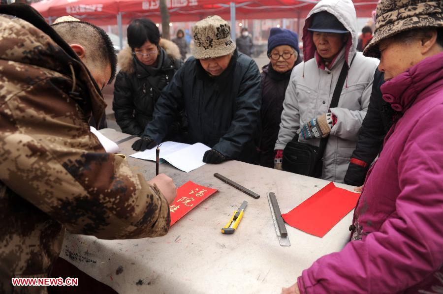 People watch a man writing couplets at a market in Shijiazhuang, capital of north China's Hebei Province, Jan. 27, 2013. The market offers local customers goods and supplies for the coming Spring Festival which falls on Feb. 10 this year.(Xinhua/Zhu Xudong)