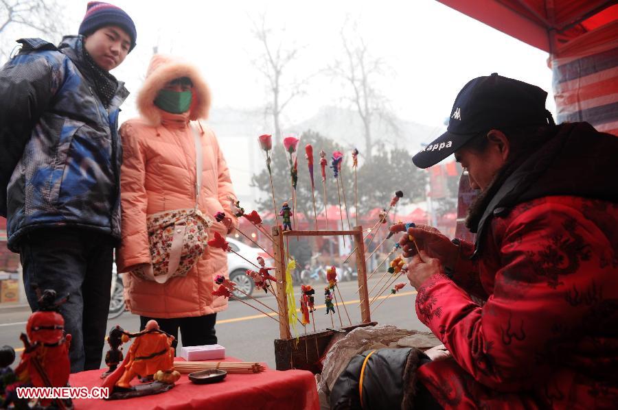 People watch a man making clay figurine at a market in Shijiazhuang, capital of north China's Hebei Province, Jan. 27, 2013. The market offers local customers goods and supplies for the coming Spring Festival which falls on Feb. 10 this year.(Xinhua/Zhu Xudong)