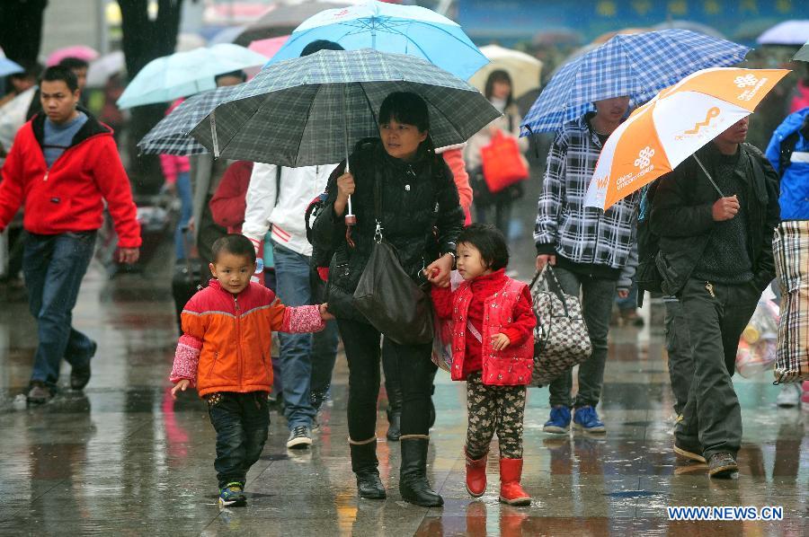 A parent walks in the rain with two children on the square of the Nanning Railway Station in Nanning, capital of south China's Guangxi Zhuang Autonomous Region, Jan. 26, 2013. As the Spring Festival, which falls on Feb. 10 this year, draws near, lots of people rushed to start their journey home. (Xinhua/Huang Xiaobang)