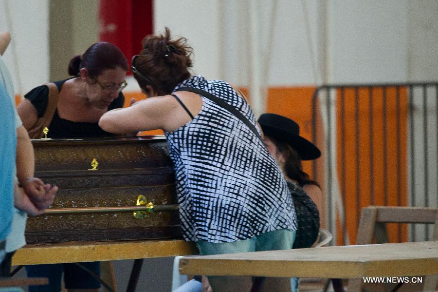 Relatives of a victim mourn over a coffin in the municipal sports center where the bodies of the nightclub fire victims are placed, in Santa Maria, state of Rio Grande do Sul, southern Brazil, on Jan. 27, 2013. A nightclub fire that broke out in Santa Maria early Sunday killed at least 245 people, according to a local TV report. (Xinhua/AGENCIA ESTADO) 