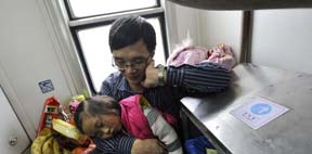 A girl falls asleep in arms of her father on the train heading to Chongqing.