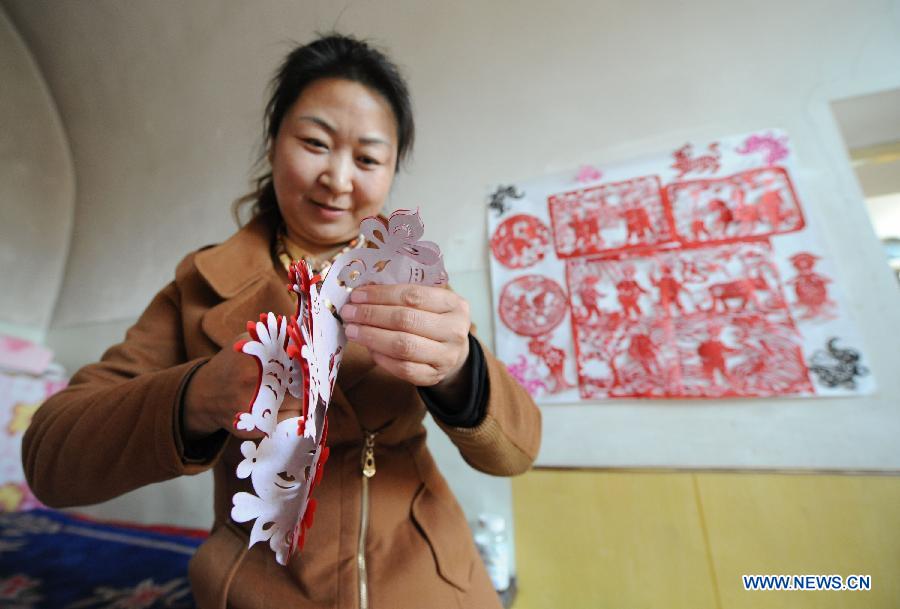 Wang Xiang'ai makes a paper cutting in Shenmu County of northwest China's Shaanxi Province, Jan. 28, 2013. People began to make paper cuttings for the decoration of the upcoming Spring Festival here in recent days. (Xinhua/Li Yibo)