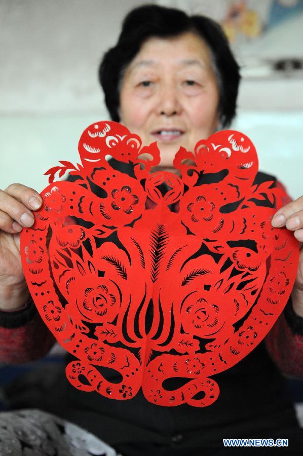 Liu Fengtang shows a piece of paper cutting work she made in Shenmu County of northwest China's Shaanxi Province, Jan. 28, 2013. People began to make paper cuttings for the decoration of the upcoming Spring Festival here in recent days. (Xinhua/Li Yibo) 