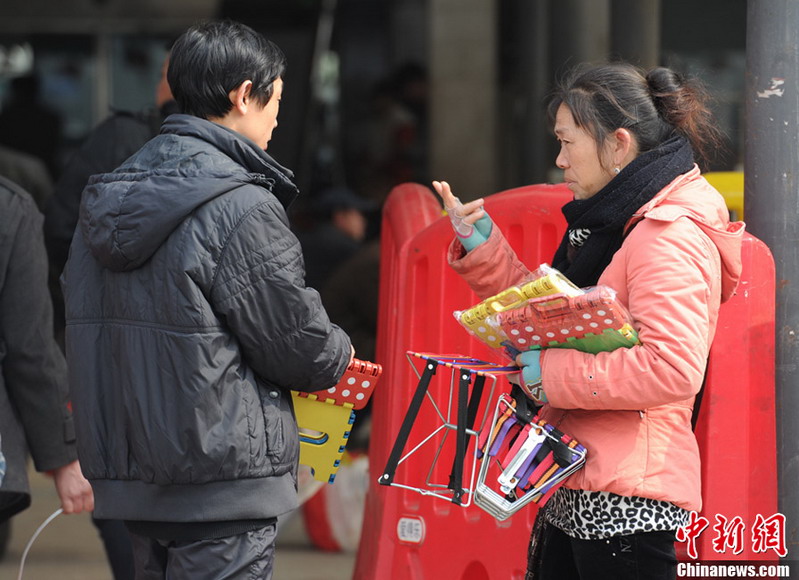 Hot sale: A traveler bargains the price of a "folding stool" with vendor before getting on train at Changshang Railway station on Jan. 26, 2013. The portable folding stool is very helpful for travelers without seats. (CNS/Yang Hufeng)