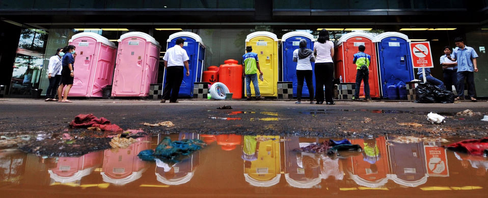People queue in front of temporary toilets as the toilets in the office building are damaged by flood waters in Jakarta, Indonesia, Jan. 23, 2013. (Xinhua/Agung Kuncahya B.)