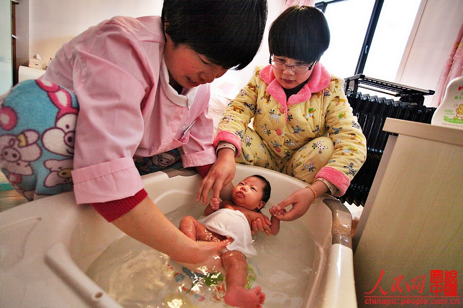 Zhang bathes the baby and talks to her at the same time.