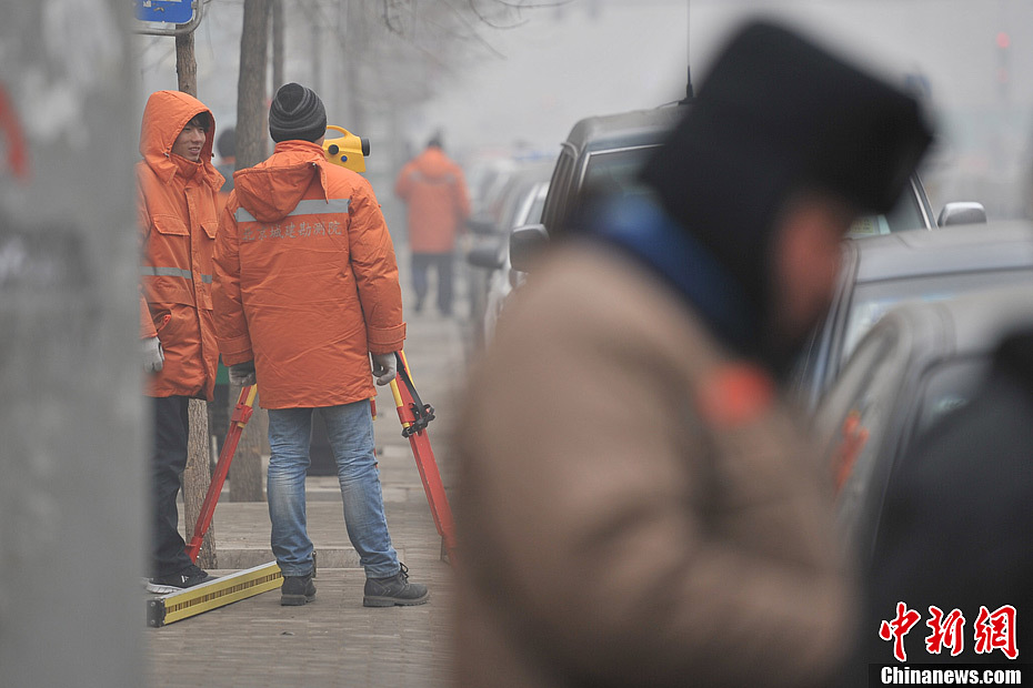 A photo taken on Jan. 29 shows two surveyors working in the foggy weather. The fourth round of heavy smog in four weeks hit Beijing on Tuesday and led to serious air pollution, which has sent more people with respiratory illnesses to hospitals. However, a group of people had to stay on jobs outdoors. (Chinanews.com/Jin Shuo)