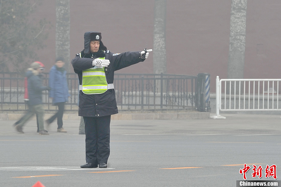 A photo taken on Jan. 29 shows a traffic policeman directing traffic in the foggy weather. The fourth round of heavy smog in four weeks hit Beijing on Tuesday and led to serious air pollution, which has sent more people with respiratory illnesses to hospitals. However, a group of people had to stay on jobs outdoors. (Chinanews.com/Jin Shuo)