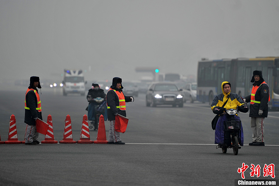 A photo taken on Jan. 29 shows three crossing guards working in the foggy weather. The fourth round of heavy smog in four weeks hit Beijing on Tuesday and led to serious air pollution, which has sent more people with respiratory illnesses to hospitals. However, a group of people had to stay on jobs outdoors. (Chinanews.com/Jin Shuo)