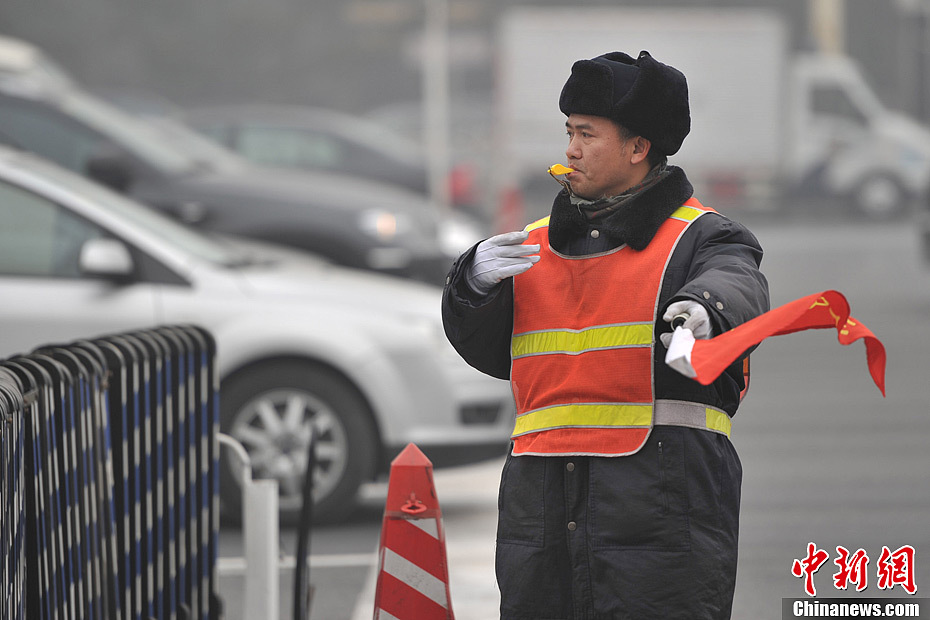 A photo taken on Jan. 29 shows a crossing guard working in the foggy weather. The fourth round of heavy smog in four weeks hit Beijing on Tuesday and led to serious air pollution, which has sent more people with respiratory illnesses to hospitals. However, a group of people had to stay on jobs outdoors. (Chinanews.com/Jin Shuo)