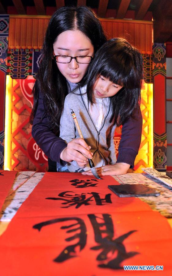 A girl learns to write on the Spring Festival couplets at a children centre in Tianjin, north China, Jan. 30, 2013. More than twenty children were invited to learn to make decorations and snacks to greet the upcoming Spring Festival which falls on Feb. 10 this year. (Xinhua/Yue Yuewei)