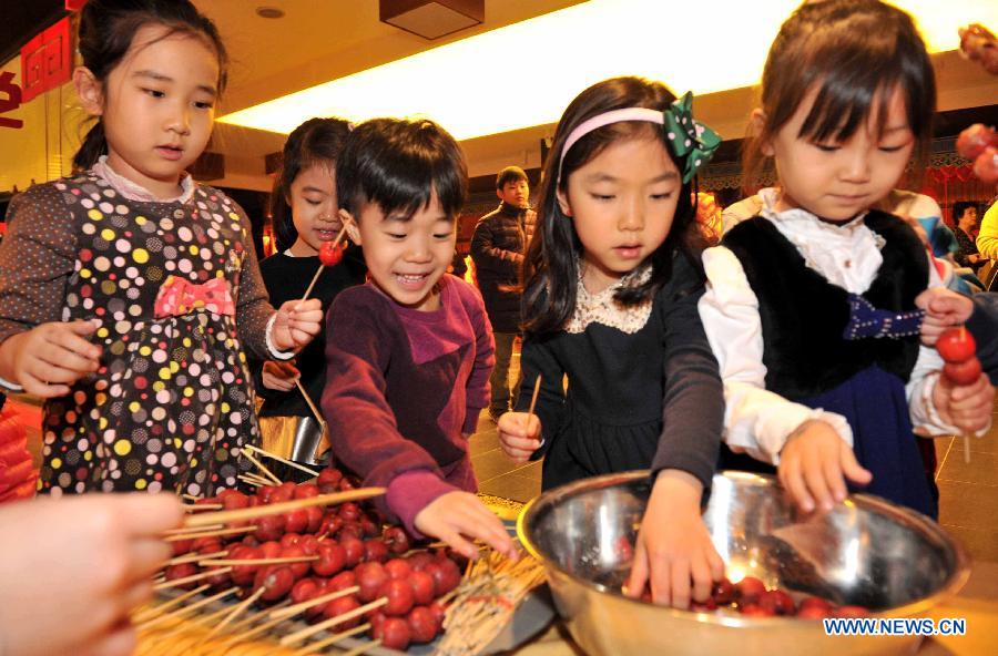 Children learn to make the "sugar-coated haws on a stick", a traditional Chinese snack, at a children centre in Tianjin, north China, Jan. 30, 2013. More than twenty children were invited to learn to make decorations and snacks to greet the upcoming Spring Festival which falls on Feb. 10 this year. (Xinhua/Yue Yuewei)