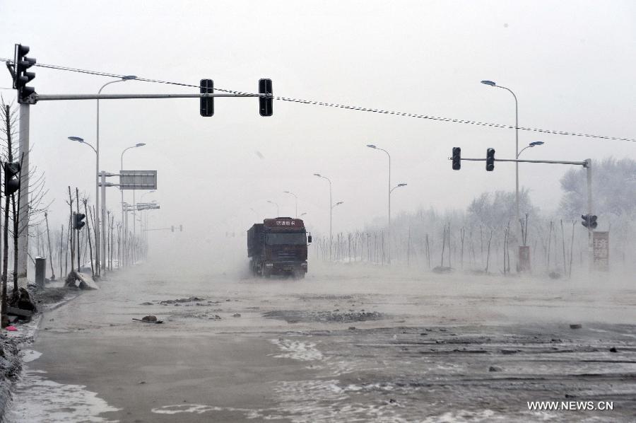 A vehicle moves on the waterlogged road after a dyke breaching accident of the Lianfeng Reservoir occured in Urumqi, capital of northwest China's Xinjiang Uygur Autonomous Region, Feb. 2, 2013. At least one person was killed and serveral injured after a dyke breaching occured at the reservior on the morning of Saturday. The rescue work is underway. (Xinhua/Zhao Ge) 