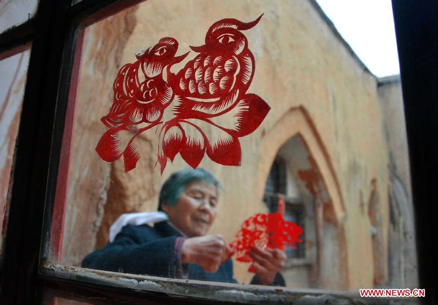 An elder makes a paper-cut outside a cave dwelling in Nangou Village of Shaanxian County, central China's Henan Province, Feb. 12, 2012. Since Chinese paper-cutting, a common fold art form, are often used to decorate doors and windows, it is also called Chuanghua, meaning Window Flower. Chinese people who live in the central China region have formed various traditions to celebrate the Chinese Lunar New Year. (Xinhua/Wang Song)