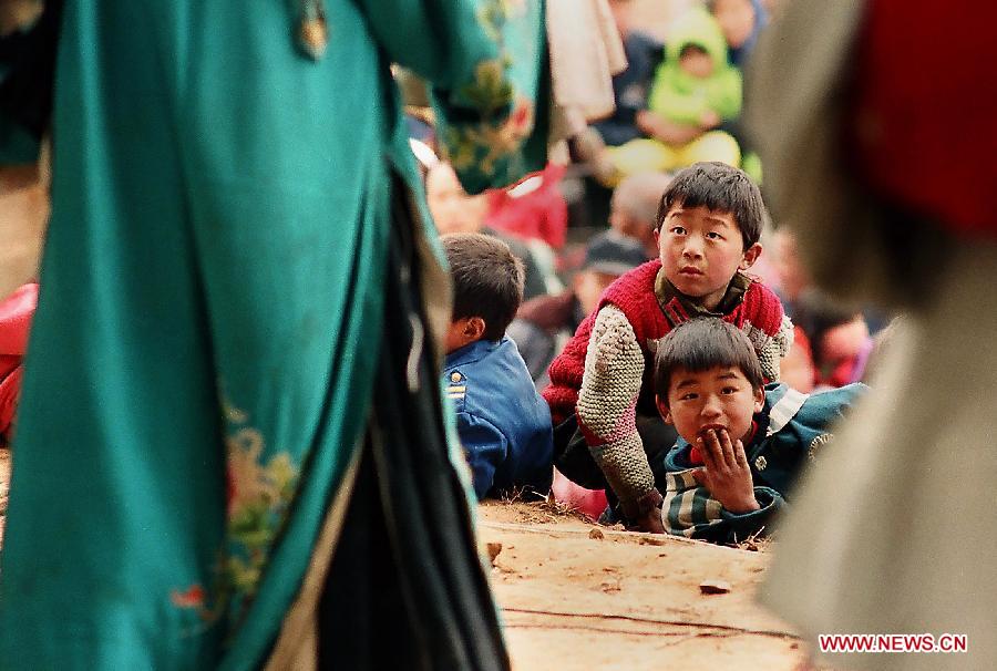 Children watch theatrical performance at an outdoor plaza in Weihui City, central China's Henan Province, Feb. 6, 2003. Village theatrical performances are usually given by local troupes during the Spring Festival or Chinese Lunar New Year in central China region. Chinese people who live in the central China region have formed various traditions to celebrate the Chinese Lunar New Year. (Xinhua/Wang Song)