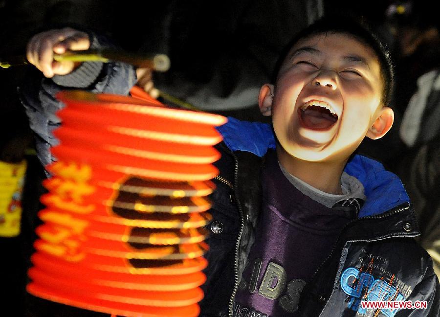 A child laughs with pleasure as he holds a newly-bought festive lantern in Zhengzhou, capital of central China's Henan Province, Feb. 1, 2011. Chinese children are usually given festive lanterns to celebrate the Spring Festival or Chinese Lunar New Year. (Xinhua/Wang Song)