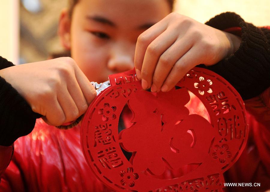 A pupil makes paper-cuttings at the Hebei Folk Arts Museum in Shijiazhuang, capital of north China's Hebei Province, Feb. 3, 2013. Pupils of Weitong Primary School were invited on Feb. 3 to present paper-cuttings at the museum to greet the upcoming Spring Festival, which falls on Feb. 10 this year. (Xinhua/Zhu Xudong)
