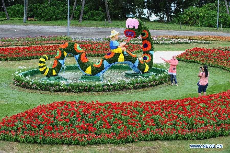 Tourists take photos with the statue made of flowers on the Sentosa Island, Singapore, Feb. 4, 2013. The flower show on the Sentosa Island to celebrate the Spring Festival opens from Feb. 9 to 17. (Xinhua/Then Chih Wey) 