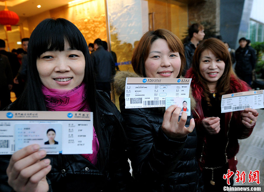 Outstanding migrant workers Li Deying and Zhu Jiangying, from Sichuan, show their boarding pass to express their happiness on Feb 3, 2013. (CNS/Liu Kegeng)