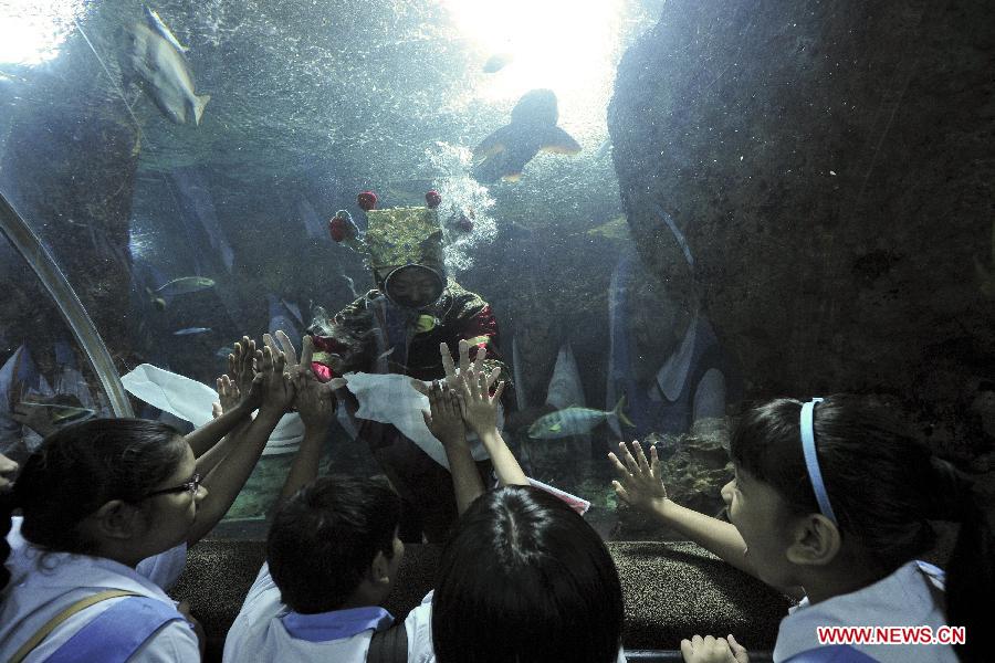 Students interact with the Chinese "God of Fortune" to receive blessings at the Underwater World in Singapore, Feb. 5, 2013. The Chinese lunar New Year is to be celebrated on Feb. 10 this year. (Xinhua/Then Chih Wey)