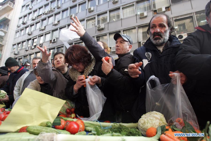 People reach out for free vegetables and fruits from farmers outside Greece's Agriculture Ministry in Athens, Greece, on Feb 6, 2013. Greek farmers continued on Wednesday their 10-day protests against tax hikes while distributing tons of vegetables and fruits for free to needy citizens. (Xinhua/Marios Lolos)