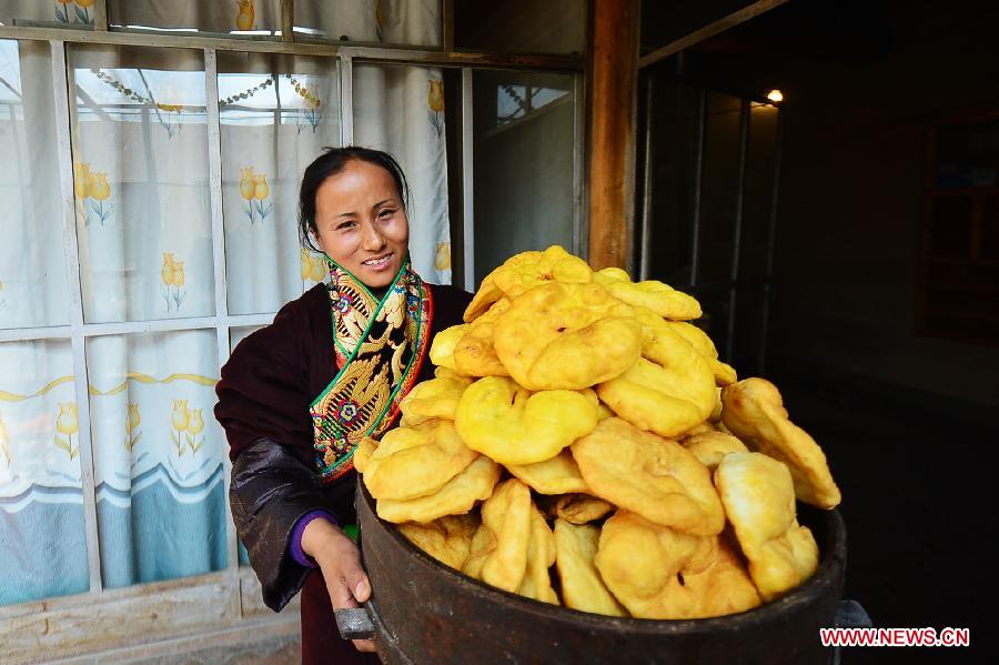 A Tibetan woman carries deep-fried dough cakes prepared for Tibetan New Year in Xiapai Village at Guide County, northwest China's Qinghai Province, Feb. 6, 2013. The Tibetan New Year, or Losar, falls on Feb. 11 this year. (Xinhua/Wu Gang)