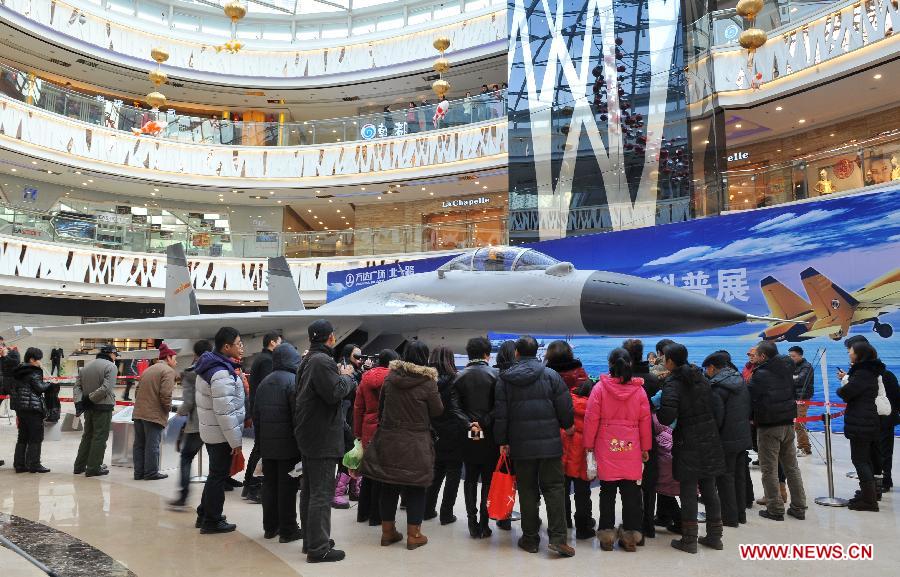 Visitors look at an aircraft model presented on the First Shenyang Aerospace Science Exhibition in Shenyang, capital of northeast China's Liaoning Province, Feb. 7, 2013. Space food, devices, models of Shenzhou spacecraft and China-developped rockets are among the exhibits. (Xinhua/Pan Enzhan)