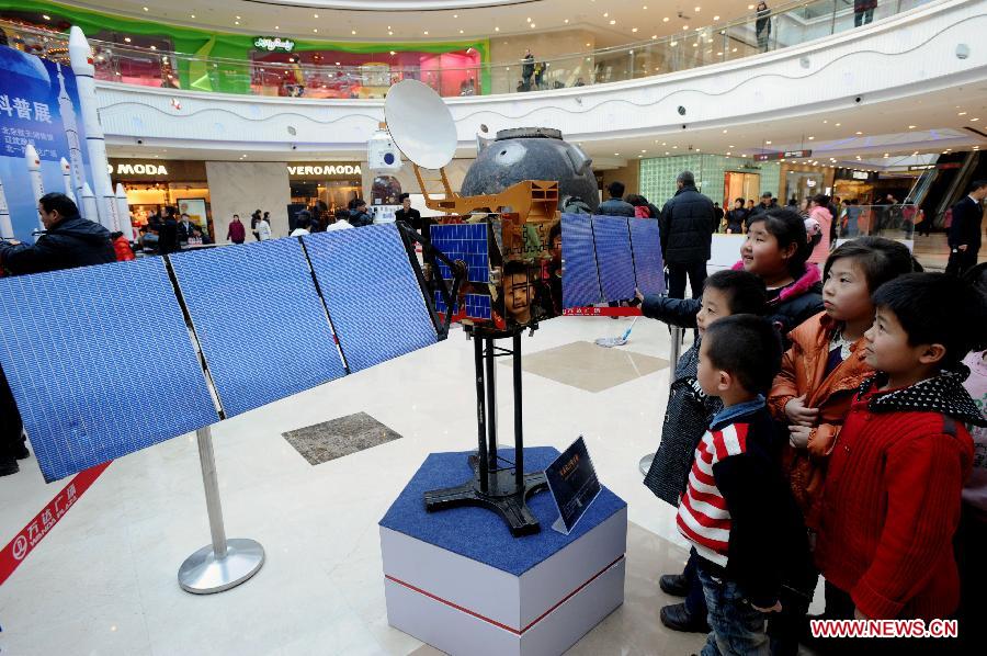 Visitors look at a model of Dongfanghong 3 satellite presented on the First Shenyang Aerospace Science Exhibition in Shenyang, capital of northeast China's Liaoning Province, Feb. 7, 2013. Space food, devices, models of Shenzhou spacecraft and China-developped rockets are among the exhibits. (Xinhua/Zhang Wenkui)