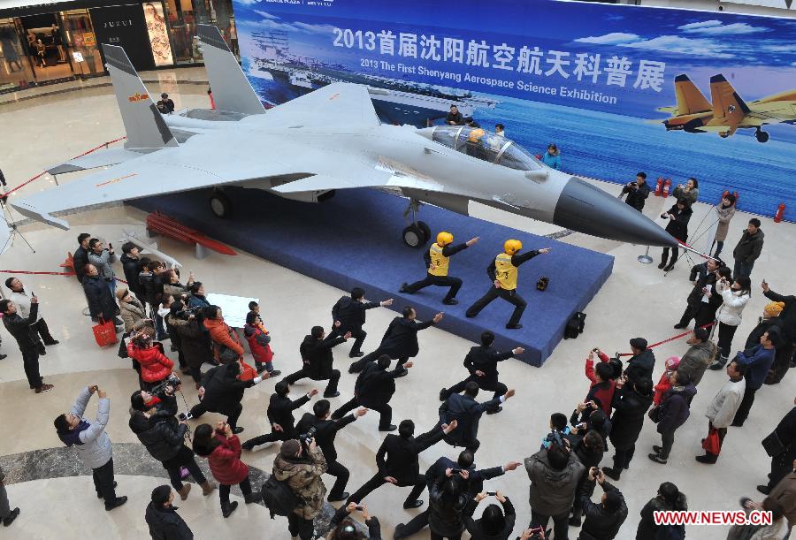 Working staff pose for photo in front of an aircraft model during the First Shenyang Aerospace Science Exhibition in Shenyang, capital of northeast China's Liaoning Province, Feb. 7, 2013. Space food, devices, models of Shenzhou spacecraft and China-developped rockets are among the exhibits. (Xinhua/Pan Enzhan)