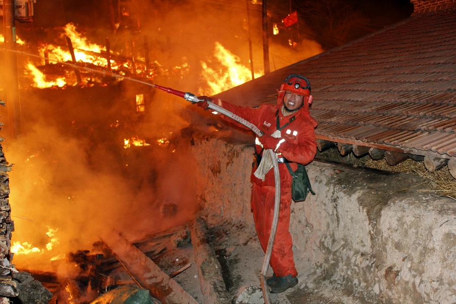 A soldier fights fires at the scene of a fire in Heiduo Village of Diebu County in northwest China's Gansu Province, Feb. 7, 2013. The fire broke out in Heiduo Village around 8 p.m. and was put out Thursday morning, leaving destruction of 92 homes and no casualties. (Xinhua/Liu Wenchao)