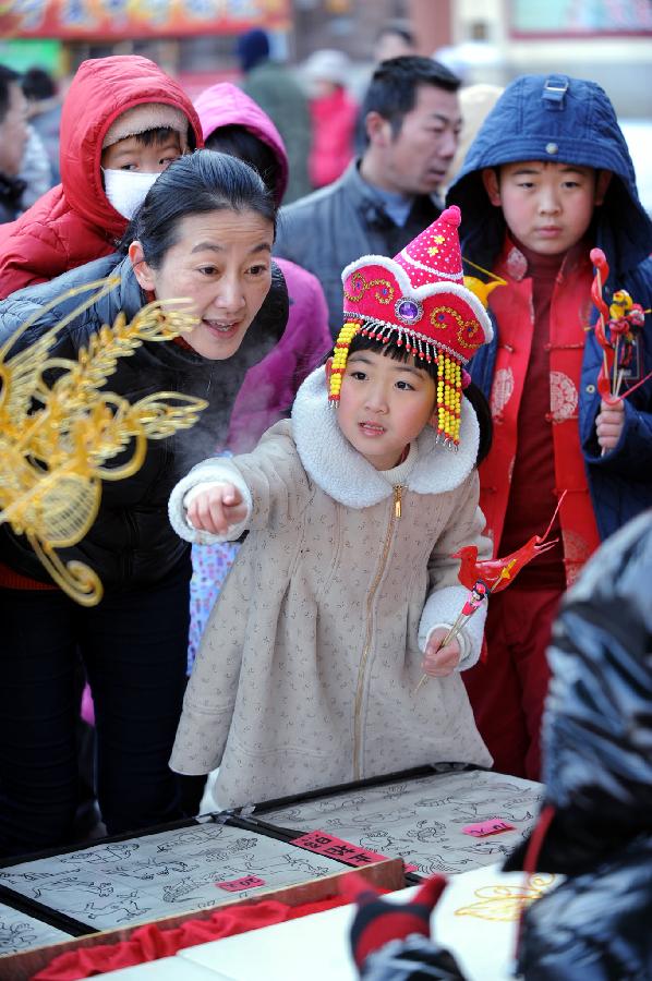 A girl (C) looks at a sugar sculpture at a temple fair celebrating Chinese Lunar New Year, or the Spring Festival, in Shenyang, capital of northeast China's Liaoning Province, Feb. 10, 2013. Various activities were held all over China on Sunday to celebrate the Spring Festival, marking the start of Chinese lunar Year of the snake. The Spring Festival falls on Feb. 10 this year. (Xinhua/Yang Xinyue) 