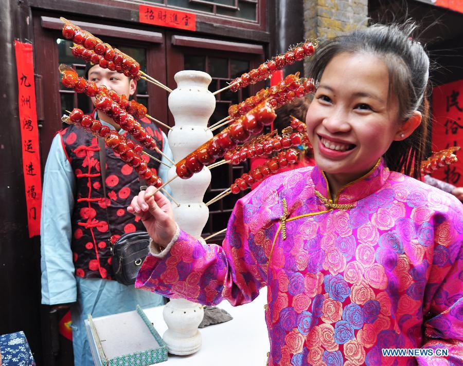 A foreign student from Laos poses for a photo with sugar-coated haws during her visit to Zhoucun District of Zibo City, east China's Shandong Province, Feb. 10, 2013. Over 20 foreign students from different countries came to the ancient town on Sunday to celebrate the Spring Festival with local people. The Spring Festival falls on Feb. 10 this year. (Xinhua/Dong Naide) 