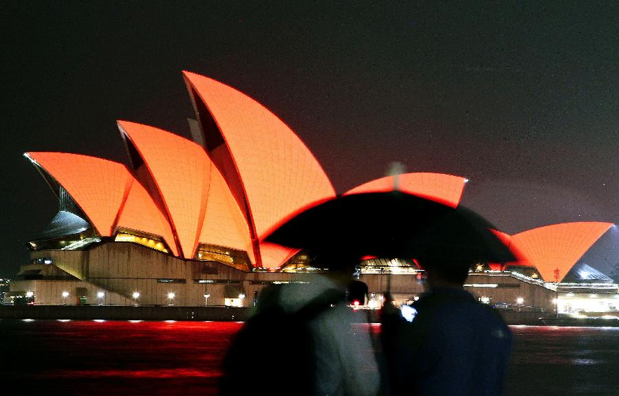 Two tourists view the Sydney Opera House, which is lit up in red to celebrate the Chinese lunar New Year, in Sydney, Australia, on Feb. 10, 2013. The Chinese Spring Festival falls on Feb. 10 this year, marking the start of the Chinese Year of the Snake. (Xinhua/Jin Linpeng) 