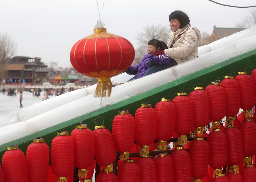 A mother and her daughter play slide at the Shichahai Lake Ice Rink on the first day of the Chinese Lunar New Year in Beijing, capital of China, Feb. 10, 2013. Many people here chose to spend the first day of the Chinese Lunar New Year on the ice. (Xinhua/Chen Xiaogen)