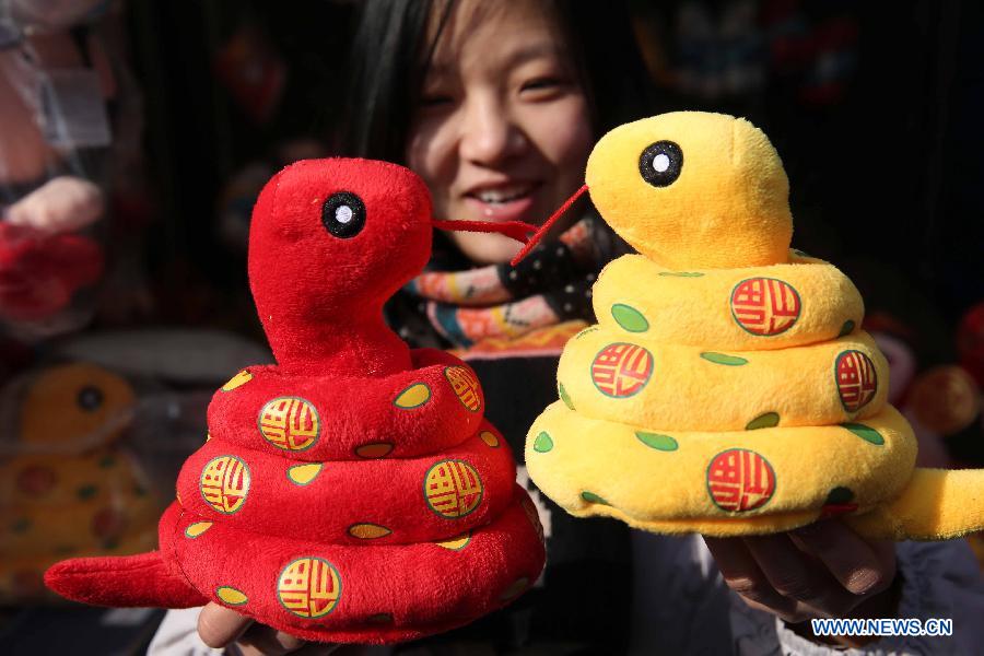 A visitor views the snake-shaped plush toys at a temple fair held to celebrate the Spring Festival, or the Chinese Lunar New Year, in Beijing, capital of China, Feb. 12, 2013. (Xinhua/Chen Xiaogen)