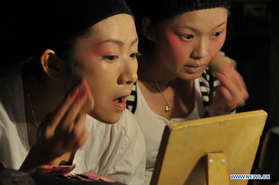 Performers put on makeup before the performance in Songmei Village of Lingao County, south China's Hainan Province, Feb. 14, 2013. A group of performers from Hainan Opera Theatre went on a ten-day tour performance in ten villages of Hainan Province. (Xinhua/Wei Hua) 