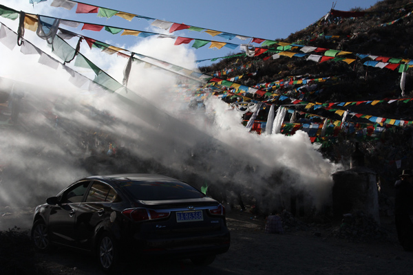 People drives a car to hang up their new sutra flags and burn melberry leaves on the passway of high mountains in the hope of getting their thoughts across to the God. [Photo/China Tibet Online]