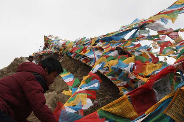Two Tibetan young men went to the second highest peak of the mountain where the Yumbu Lhakhang Palace locates to hang up their sutra streamers. It is said the higher the streamers are put, the lounder the prayer could get to the dieties in heaven. [Photo/China Tibet Online]