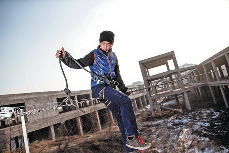 Dubbed China's "No 1 Slackliner", Zhang Liang prepares to walk along a rope, over an unfinished building compound in Beijing, on a freezing day. (China Daily/An Lingjun)   