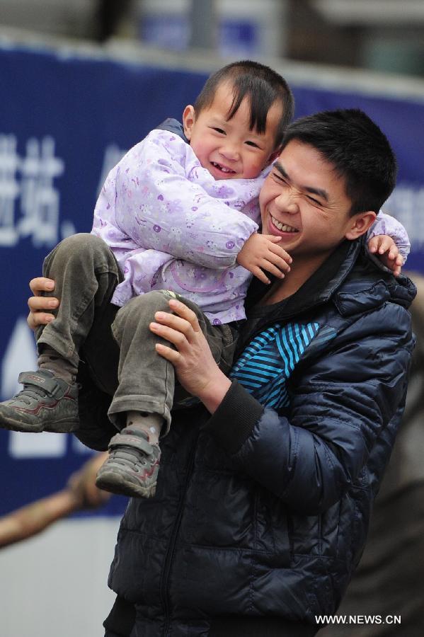 A man carries his child on the shoulder at the Guiyang Railway Station in Guiyang, capital of southwest China's Guizhou Province, Feb. 17, 2013. When the Spring Festival holiday comes to an end, migrant workers start to leave their hometowns in Guizhou for job opportunities in China's more affluent coastal provinces. Many have to take their children with them. (Xinhua/Liu Xu)