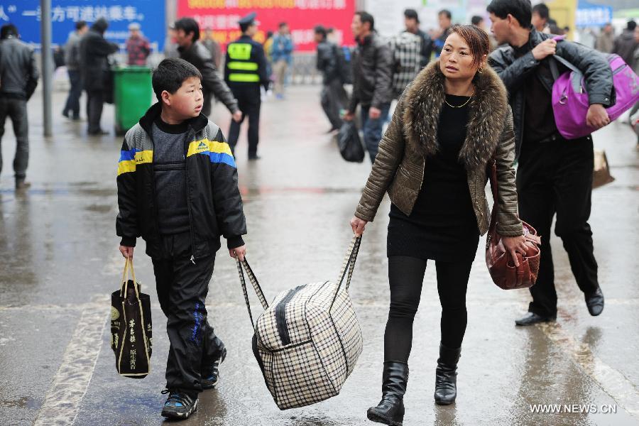 A woman and her son carry a luggage bag at the Guiyang Railway Station in Guiyang, capital of southwest China's Guizhou Province, Feb. 17, 2013. When the Spring Festival holiday comes to an end, migrant workers start to leave their hometowns in Guizhou for job opportunities in China's more affluent coastal provinces. Many have to take their children with them. (Xinhua/Liu Xu)