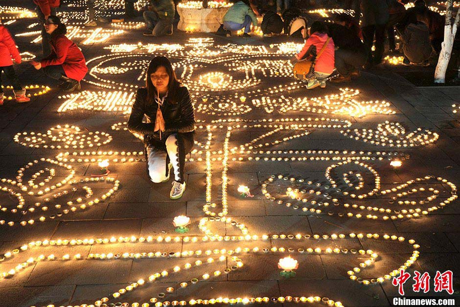 A girl prays for good fortune as tens of thousands of oil lamps are lit at the Guangren Lama Temple in Xi'an, Shaanxi Province, February 17, 2013. Many people went to the temple to pray for good fortune on Sunday. (CNS/Zhang Yuan)