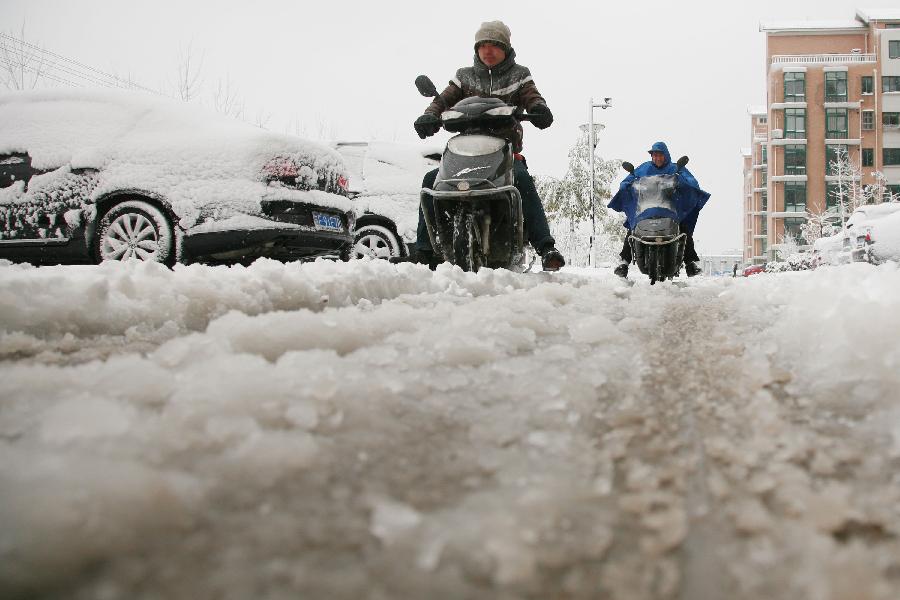 Citizens brave snow to travel on a snowy road in Nantong, east China's Jiangsu Province, Feb. 19, 2013. A snowstorm hit Jiangsu province on Feb. 19 morning and local meteorological bureau has issued a blue alert for the snowfall. (Xinhua/Cui Genyuan)